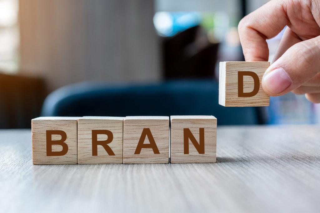 A hand places scrabble tiles spelling brand | OpenAsset