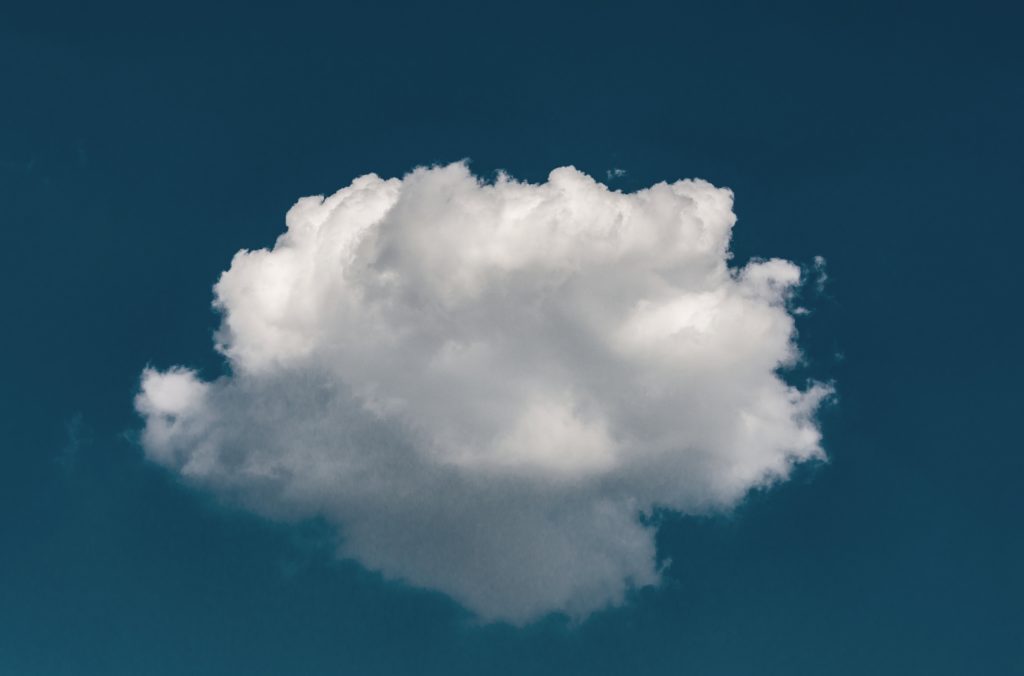 white fluffy cloud at the center of a blue sky background | OpenAsset
