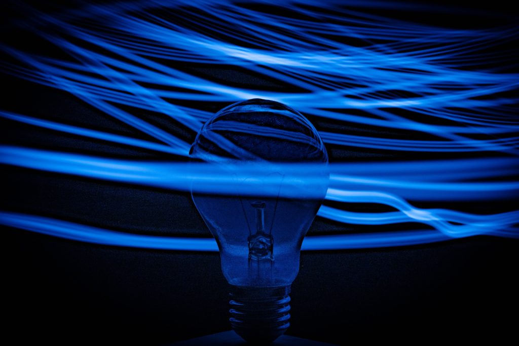blue light bulb surrounded by blue filament on black background | OpenAsset