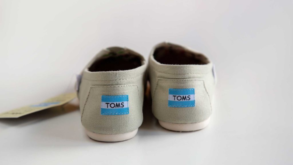 Pair of white Toms Shoes depicting logo | OpenAsset