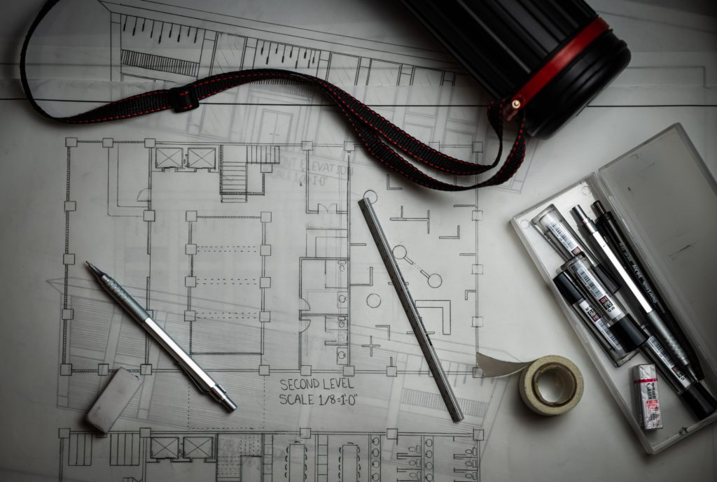 Blueprint plans with pens and camera on table | OpenAsset