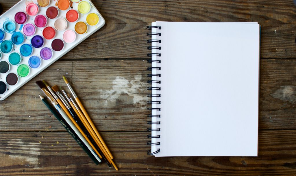 Water color paint, paint brushes and notebook on table | OpenAsset