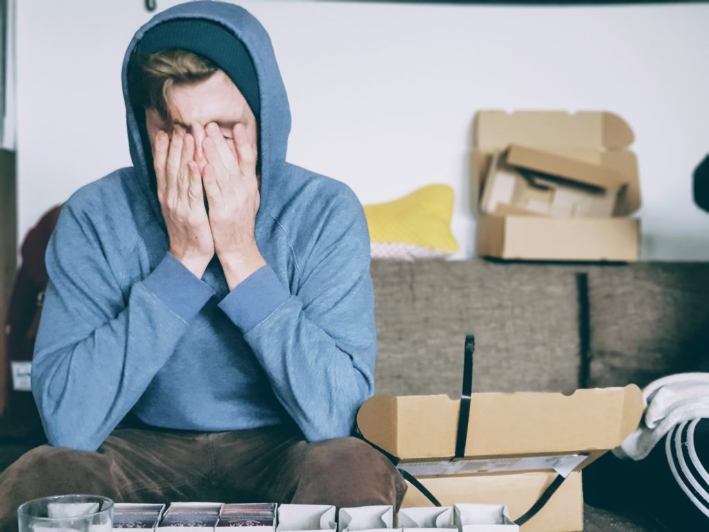 Young man in hooded sweatshirt showing signs of stress and burnout | OpenAsset