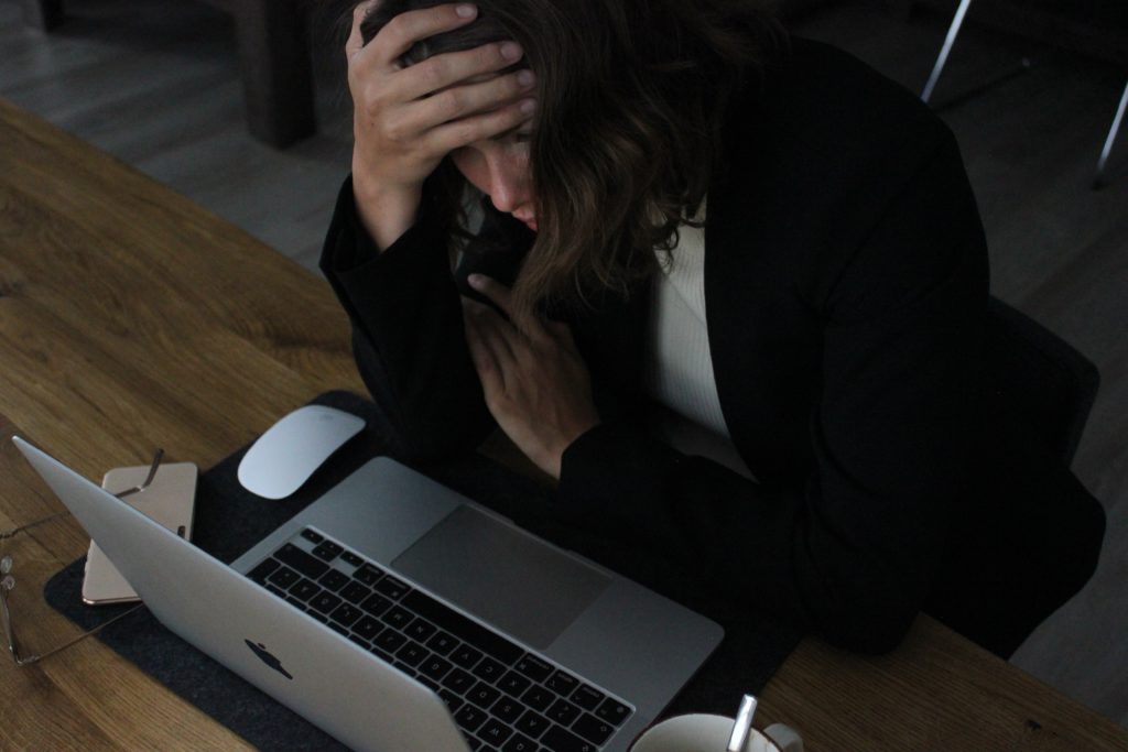 Woman working at laptop showing signs of stress | OpenAsset