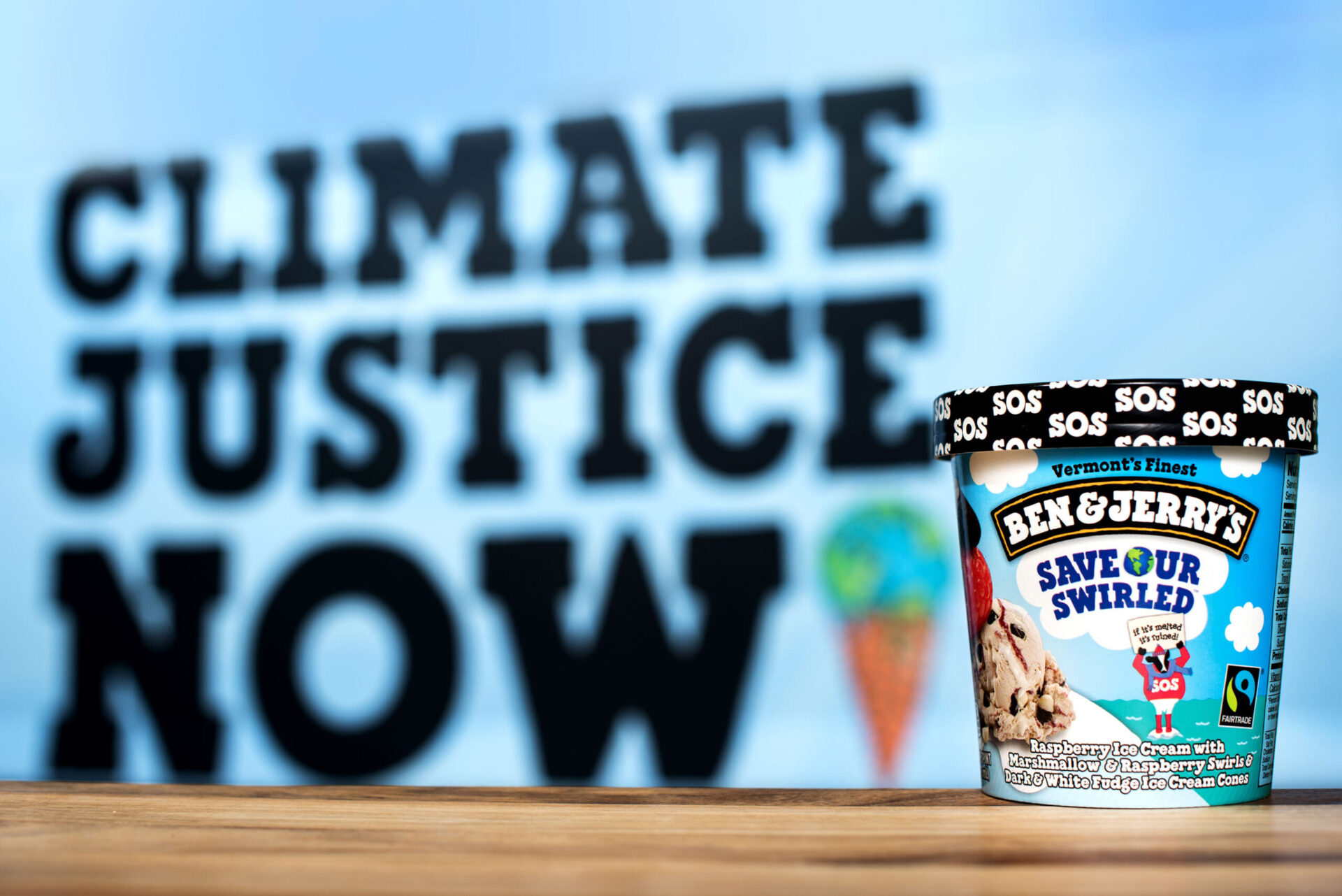A close-up of a Ben & Jerry's "save our swirled" ice cream container with the words "climate justice now" in the background