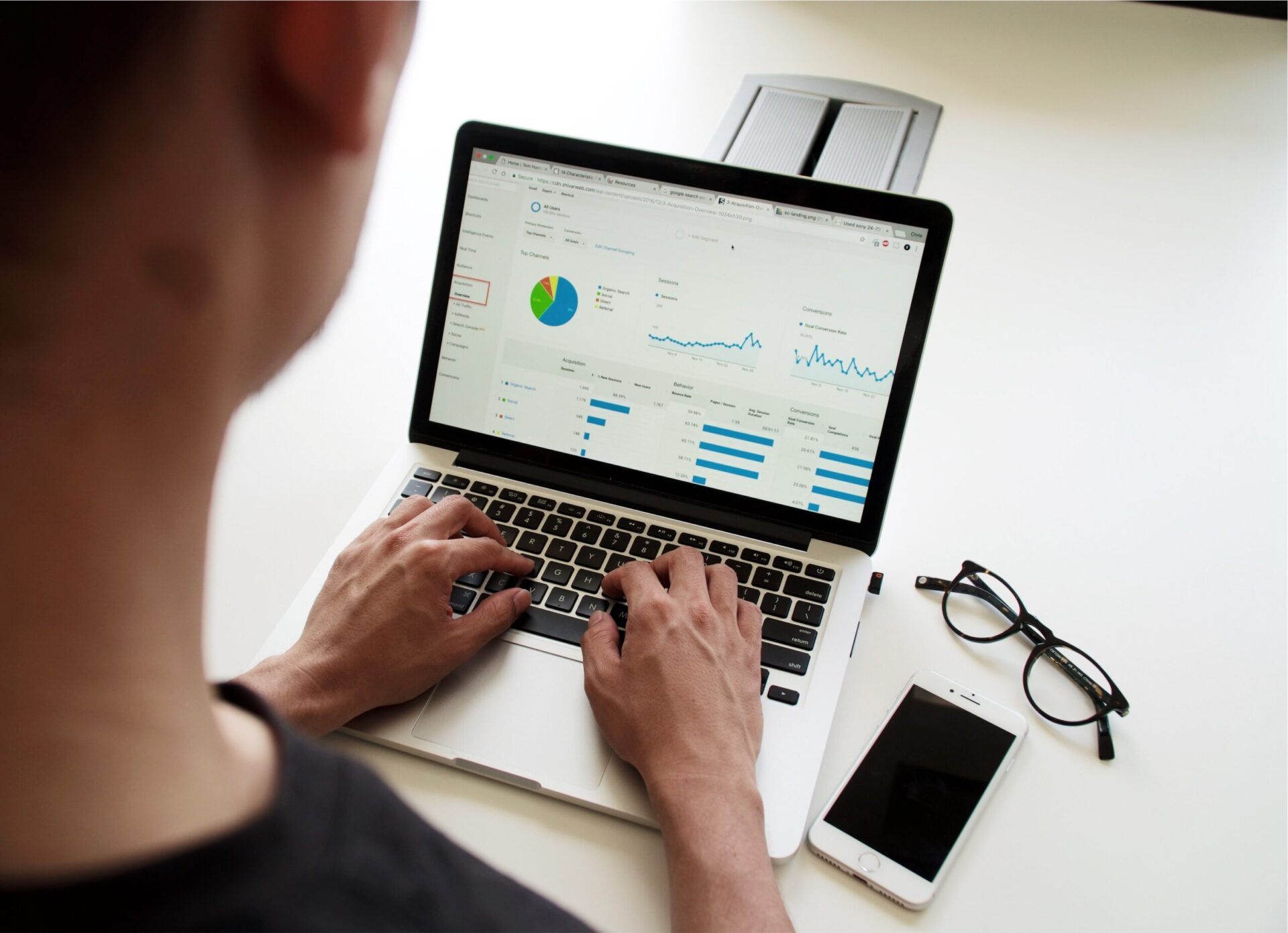 Man typing on laptop with glasses and iPhone on desk | OpenAsset