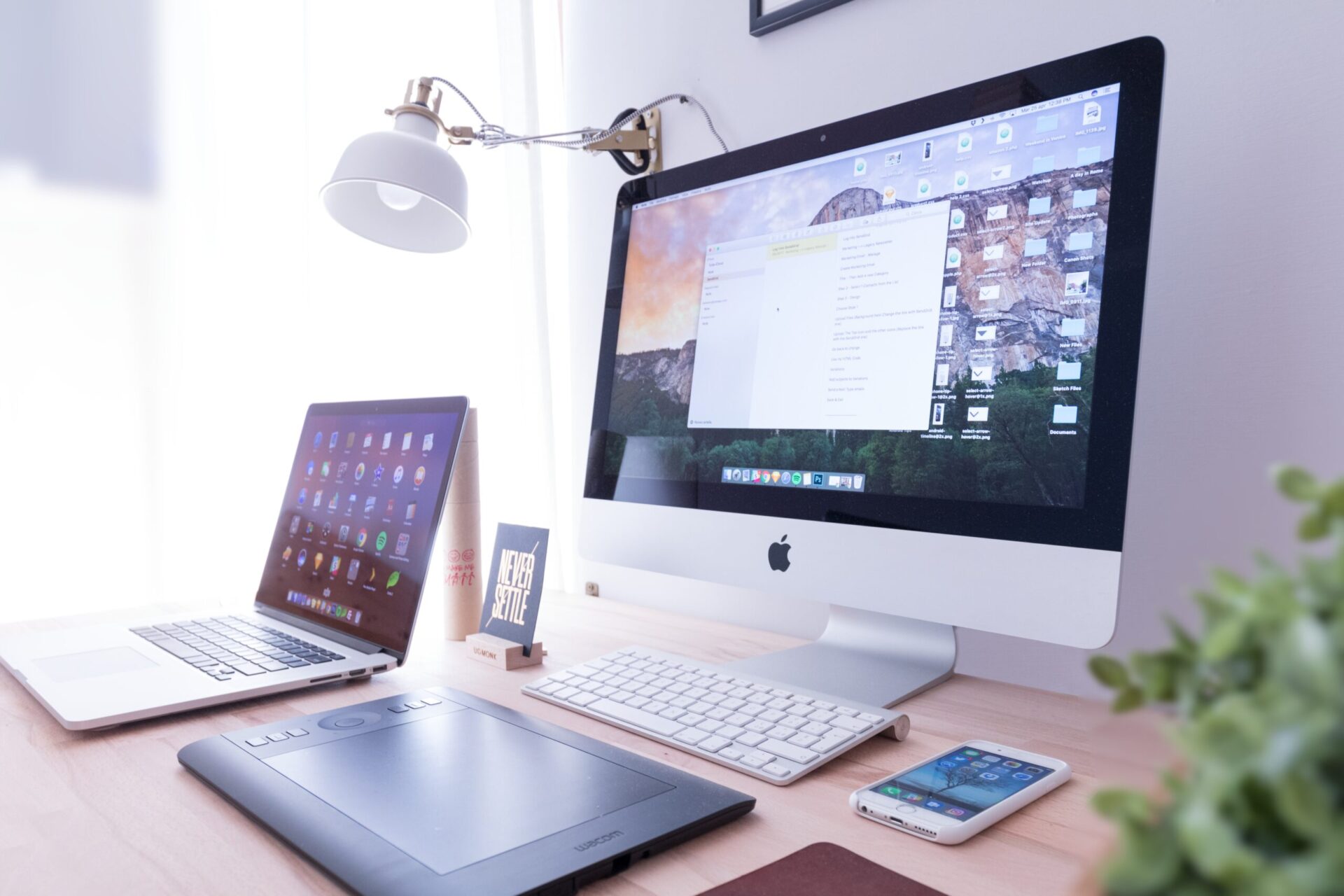 Apple laptop, iPhone and desktop computer with keyboard on desk | OpenAsset