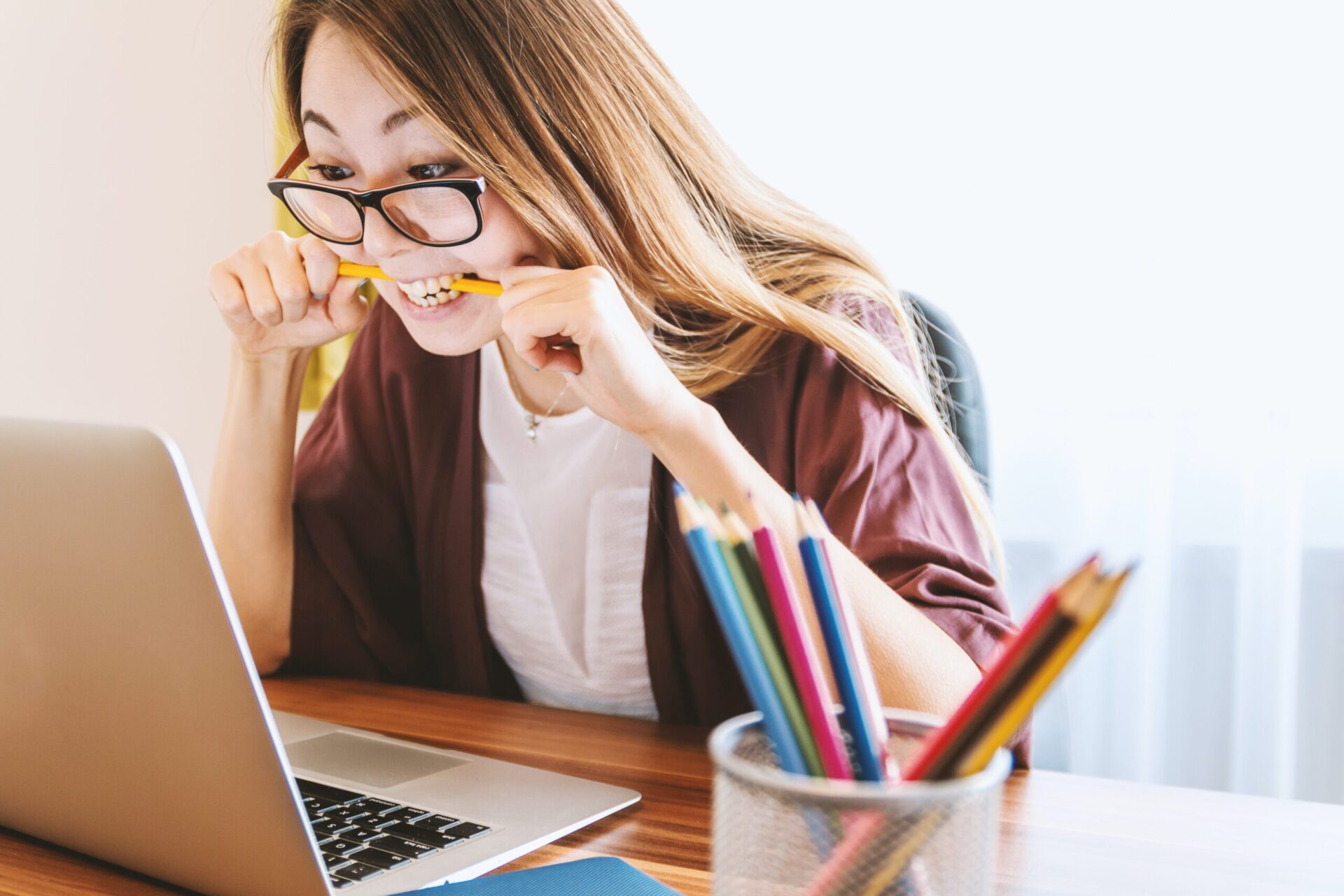 Woman working on computer, biting pencil and showing signs of burnout | OpenAsset