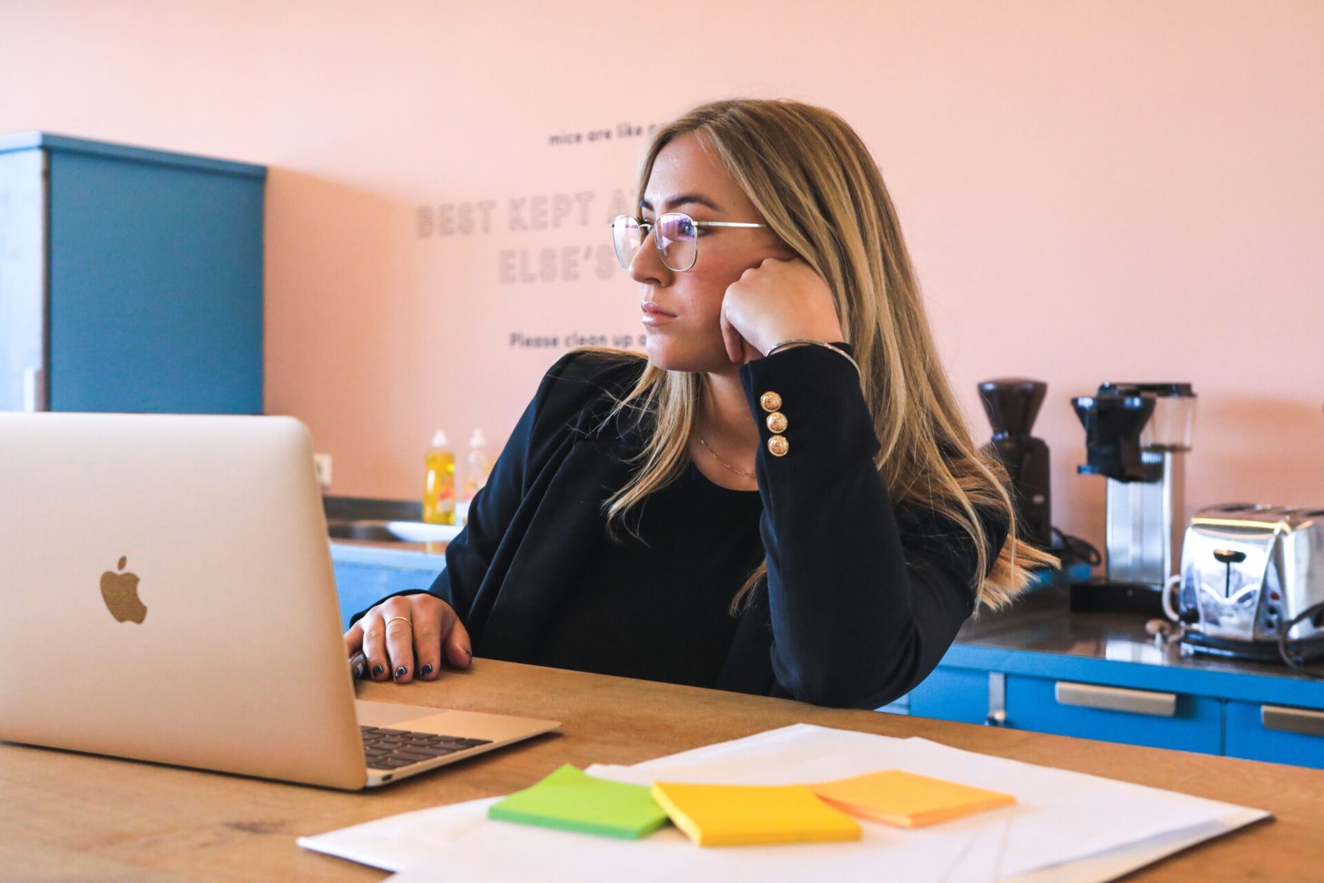 Blonde woman in business attire looks intently at a lob top screen in office break room | OpenAsset