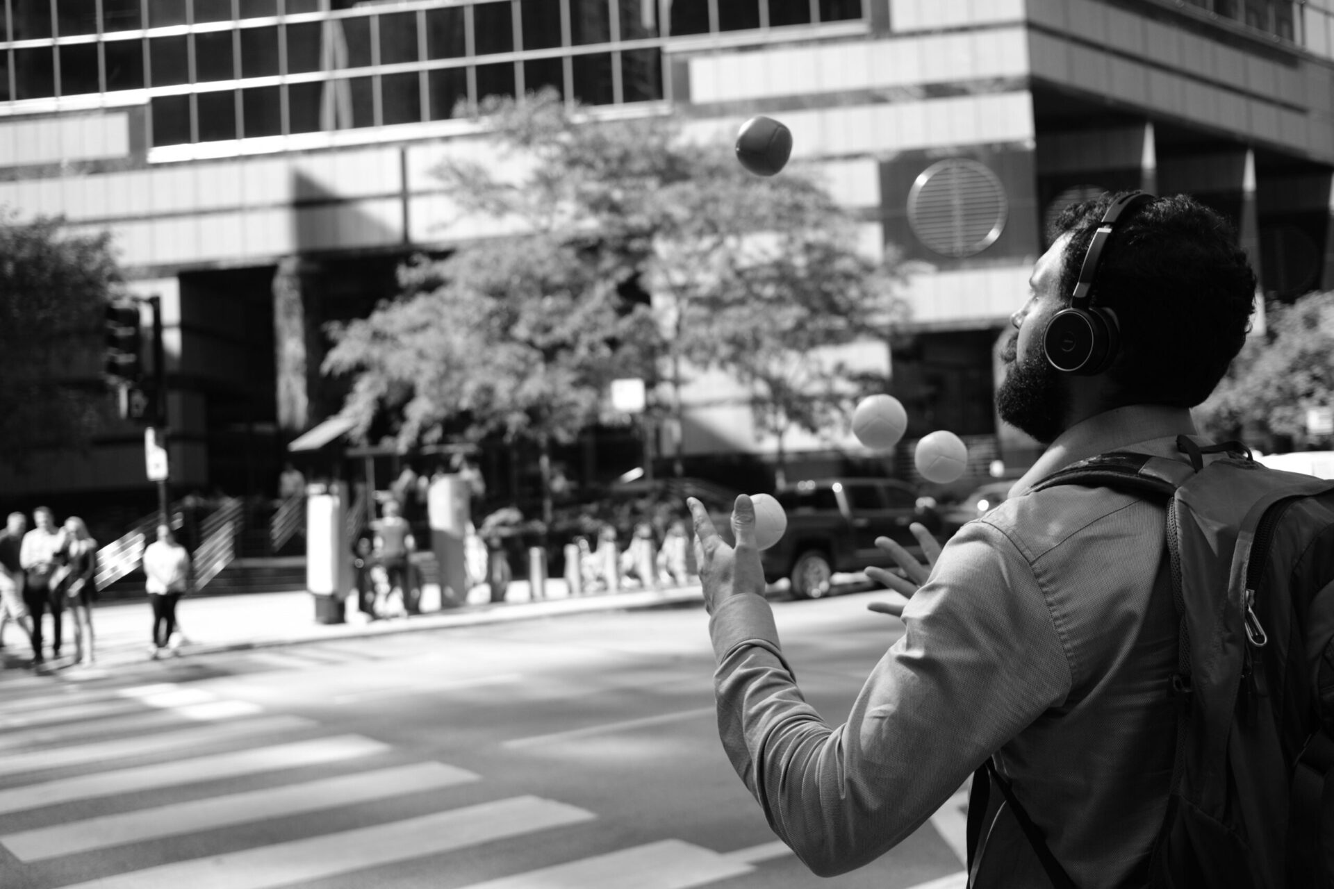 Black and White Image of Man Walking on Cross Walk and Practicing His Juggling | OpenAsset