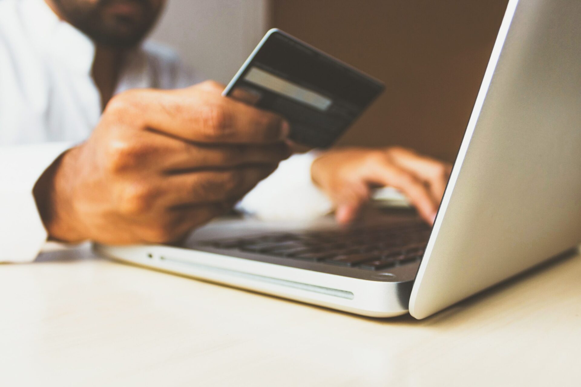 Man Holding Credit Card and Making a Purchase on Laptop | OpenAsset