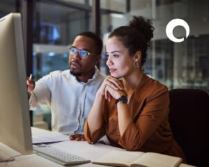 Man and woman sitting at a desk looking at a computer