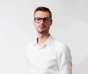 A headshot of Keith Kennedy, OpenAsset's director of AEC marketing innovation, a man wearing glasses and a white shirt on a white background.